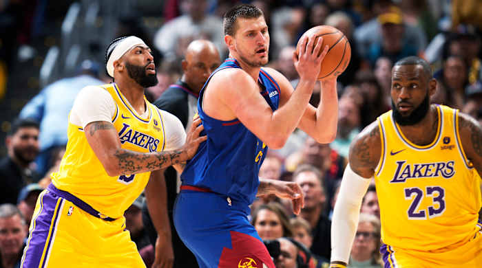 Nuggets center Nikola Jokić (center) looks to pass the ball as Los Angeles Lakers forward Anthony Davis (left) and forward LeBron James defend.